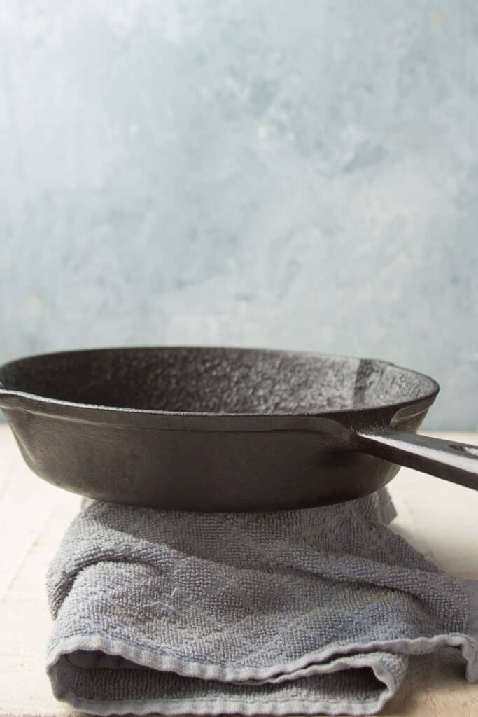 Block of Tofu Wrapped in Towel with Cast Iron Skillet on Top