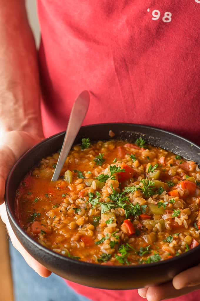 Hands Holding a Bowl of Vegan Stuffed Pepper Soup with Spoon