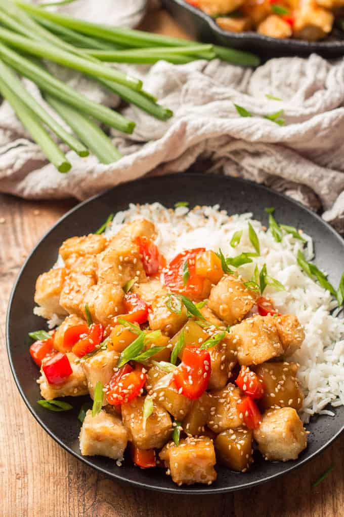 Plate of Sweet & Sour Tofu and Rice with Skillet and Bunch of Scallions in the Background