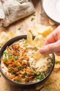 Hand Dipping a Chip into a Bowl of Vegan French Onion Dip