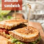 Two Halves of a Grilled Avocado Sandwich on a Cutting Board with Text Overlay Reading "Grilled Avocado Sandwich"
