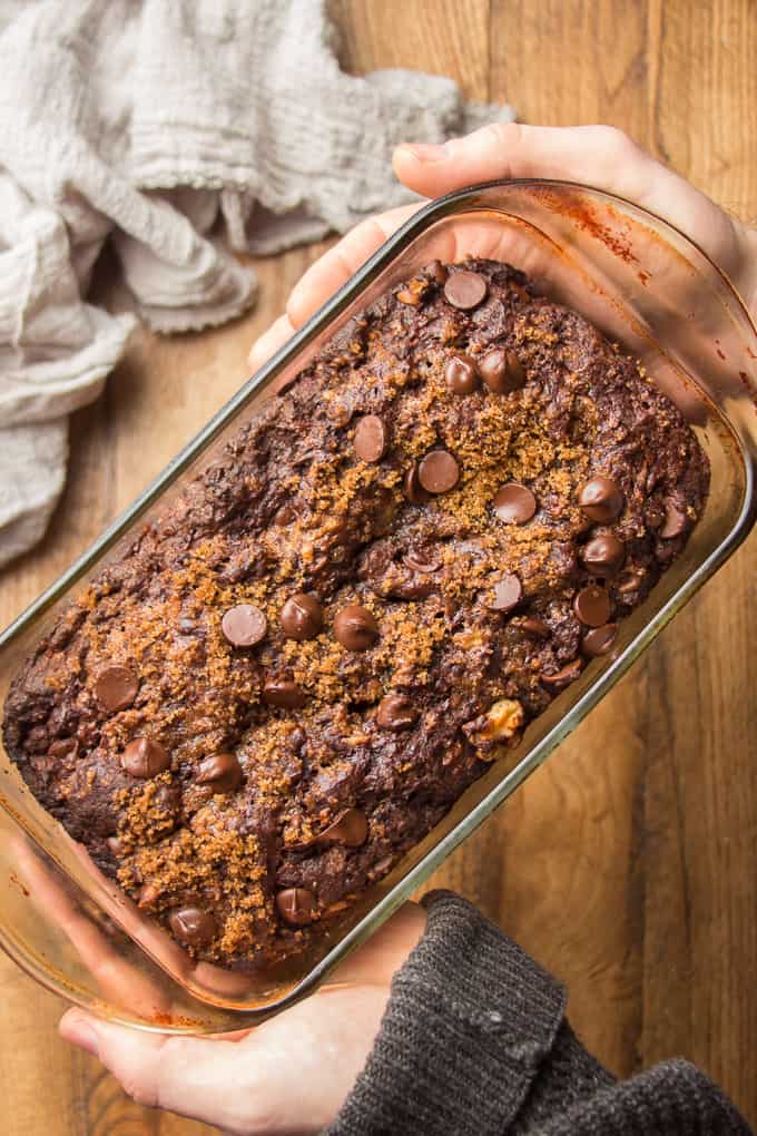 Hands Holding a Loaf of Vegan Chocolate Banana Bread in a Loaf Pan