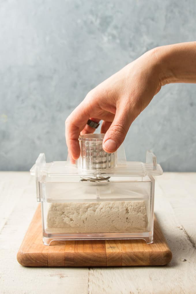 Hand Inserting Plunger into a Tofu Press Containing A Block of Tofu