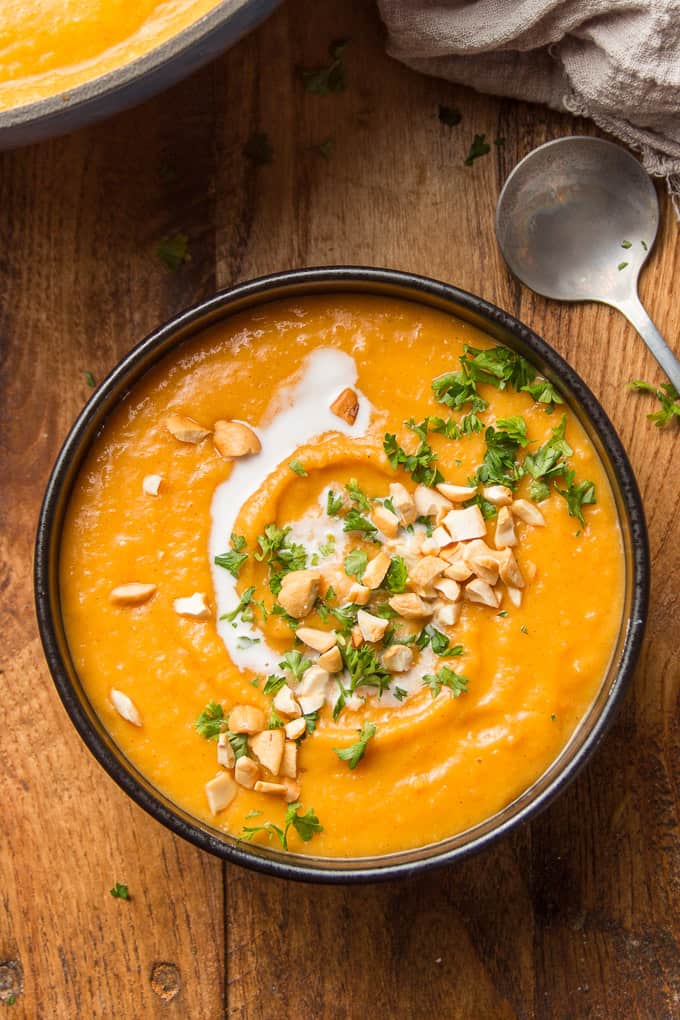 Bowl of Sweet Potato Soup with Peanuts and Parsley on Top and Spoon on the Side