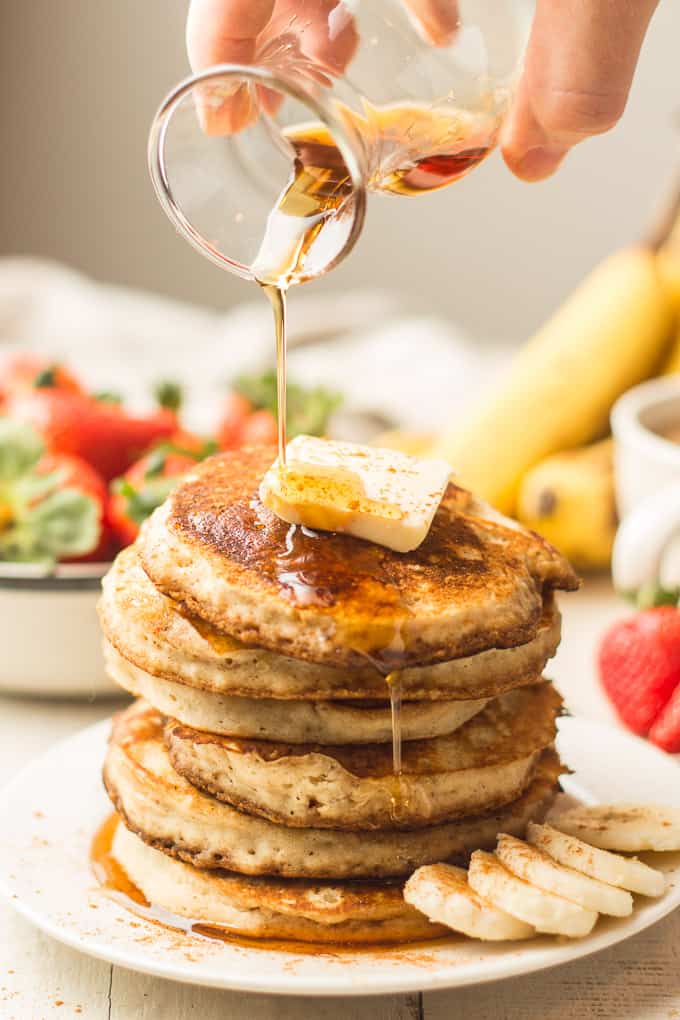 Hand Drizzling Maple Syrup Over a Stack of Vegan Banana Pancakes