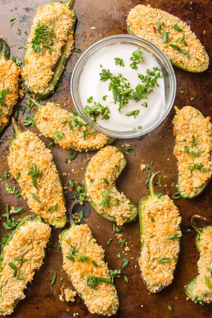 Vegan Jalapeño Poppers on a Distressed Baking Sheet with a Bowl of Dipping Sauce