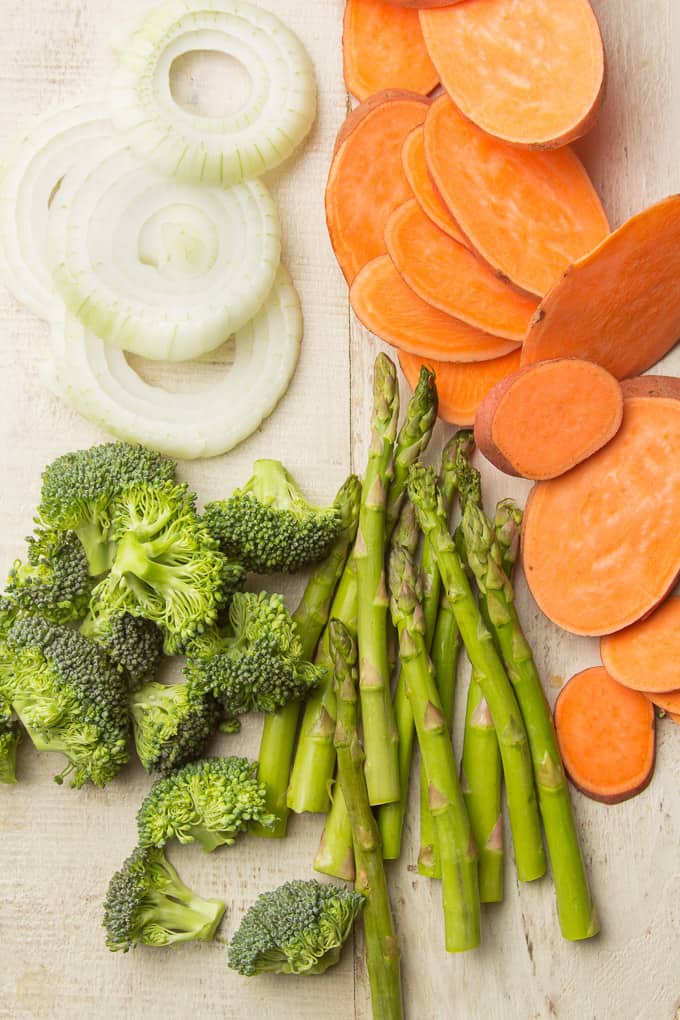 Sliced Onions, Sweet Potatoes, Broccoli Florets, and Asparagus on a White Wooden Surface
