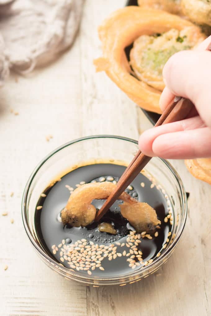 Hand Dipping a Tempura Fried Onion Ring into Sesame Soy Sauce