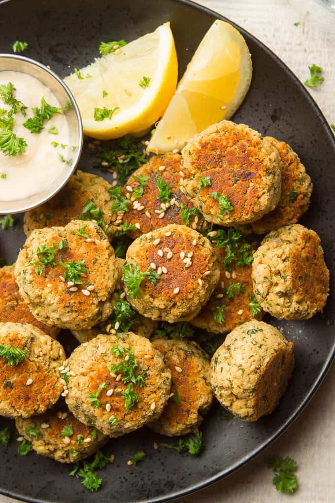 Baked Falafels Topped with Sesame Seeds and Parsley, with Hummus and Lemon Slices on the Side