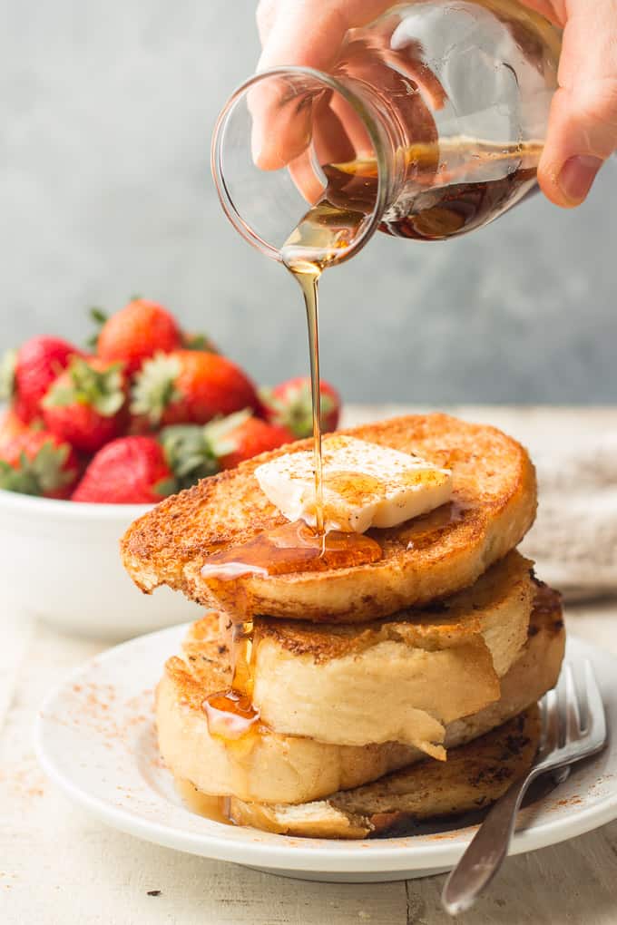 Hand Pouring Maple Syrup Over a Stack of Vegan French Toast