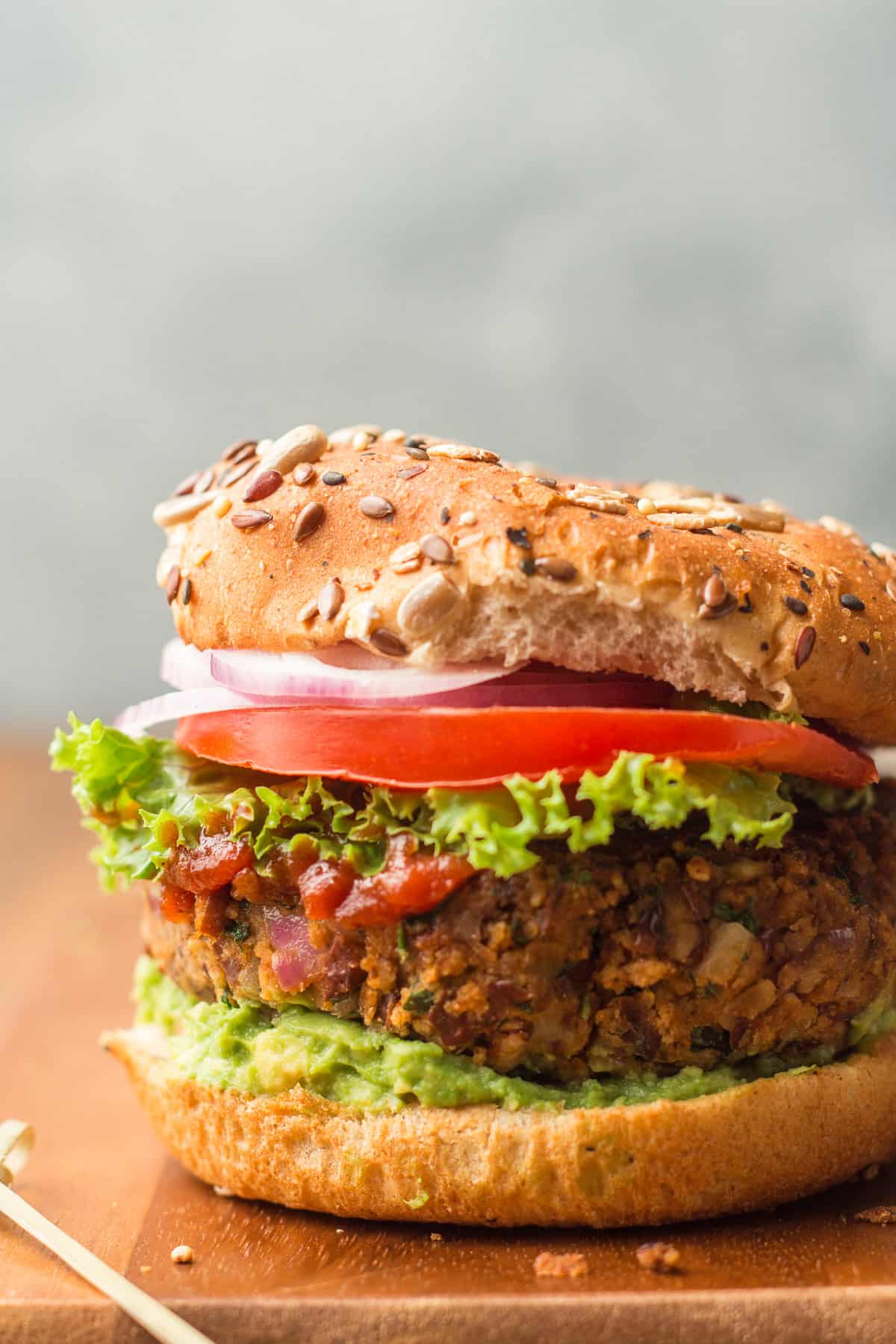 Close Up of a Black Bean Burger on a Bun with, Lettuce, Tomato, Onion, and Avocado