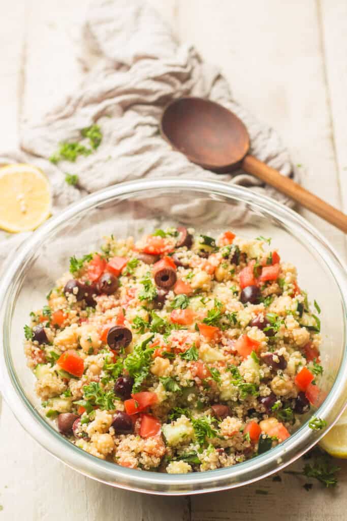 Bowl of Mediterranean Quinoa Salad with Wooden Spoon in the Background