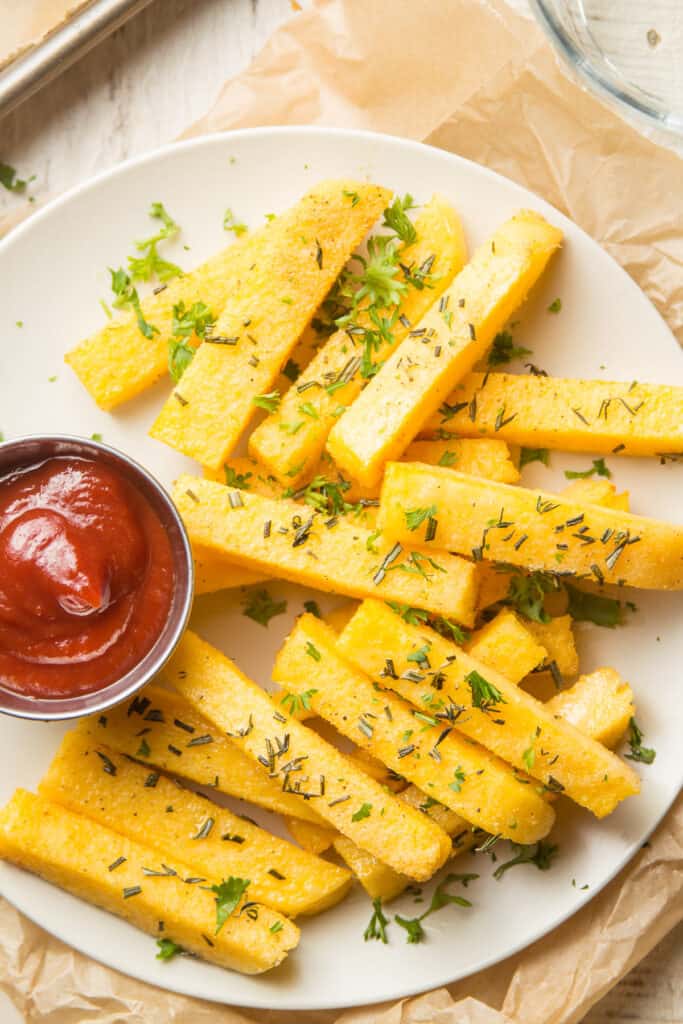 Close Up of a Plate of Herbed Polenta Fries with Dish of Ketchup
