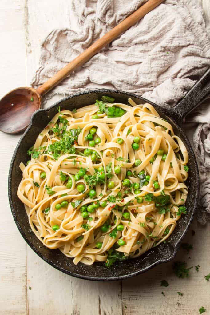 Table Set with A Skillet of White Wine Pasta, Napkin, and Wooden Spoon