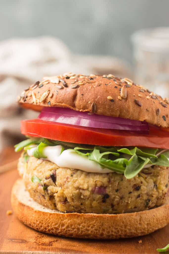 Close Up of a Greek Chickpea Burger Topped with Mayonnaise, Arugula, Lettuce and Red Onion