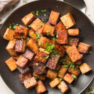 Plate of Marinated Tofu with Herbs on Top and Spoon on the Side