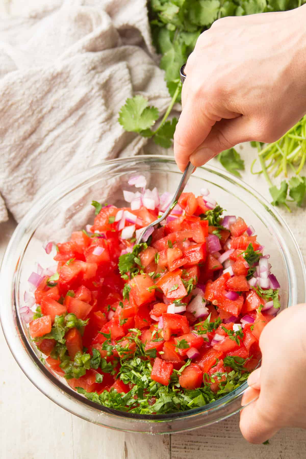 Hand Stirring Ingredients for Pico de Gallo Together in a Bowl