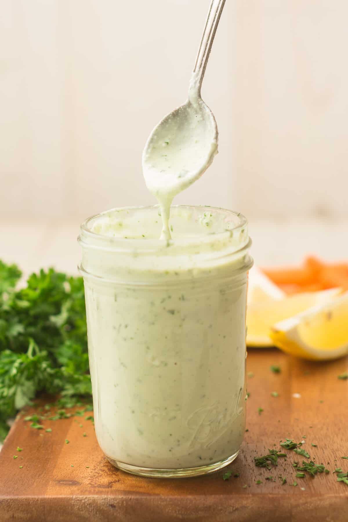Spoon Drizzling Vegan Ranch Dressing Over a Jar