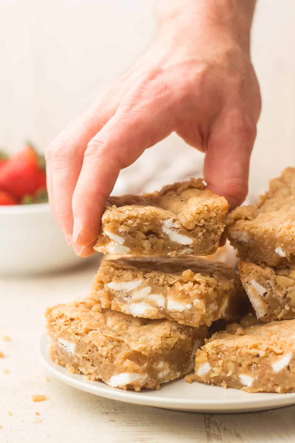Hand grabbing a vegan blondie from a plate