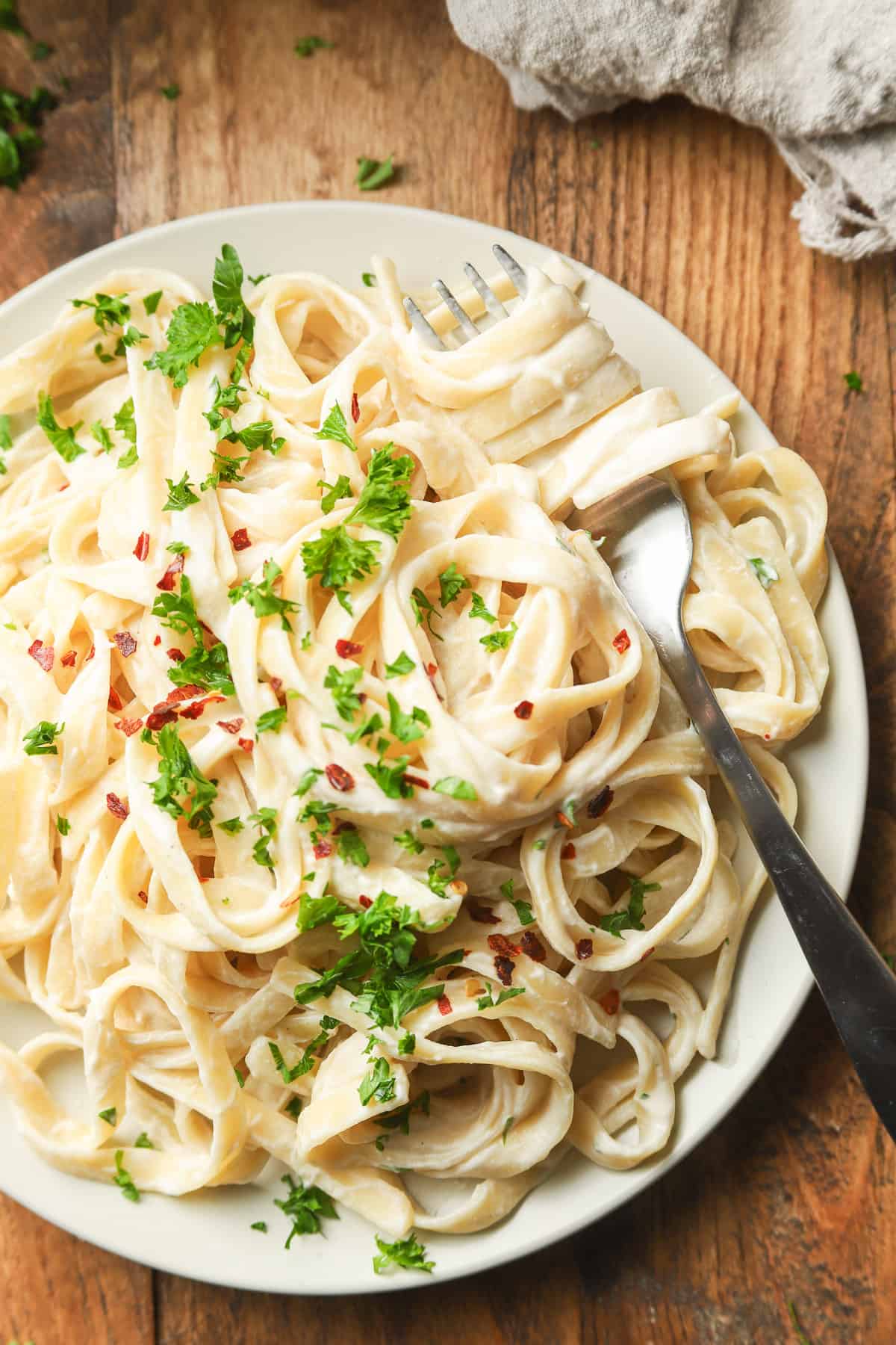 Close Up of Vegan Fettuccine Alfredo on a Plate with Cluster of Pasta Wrapped Around a Fork