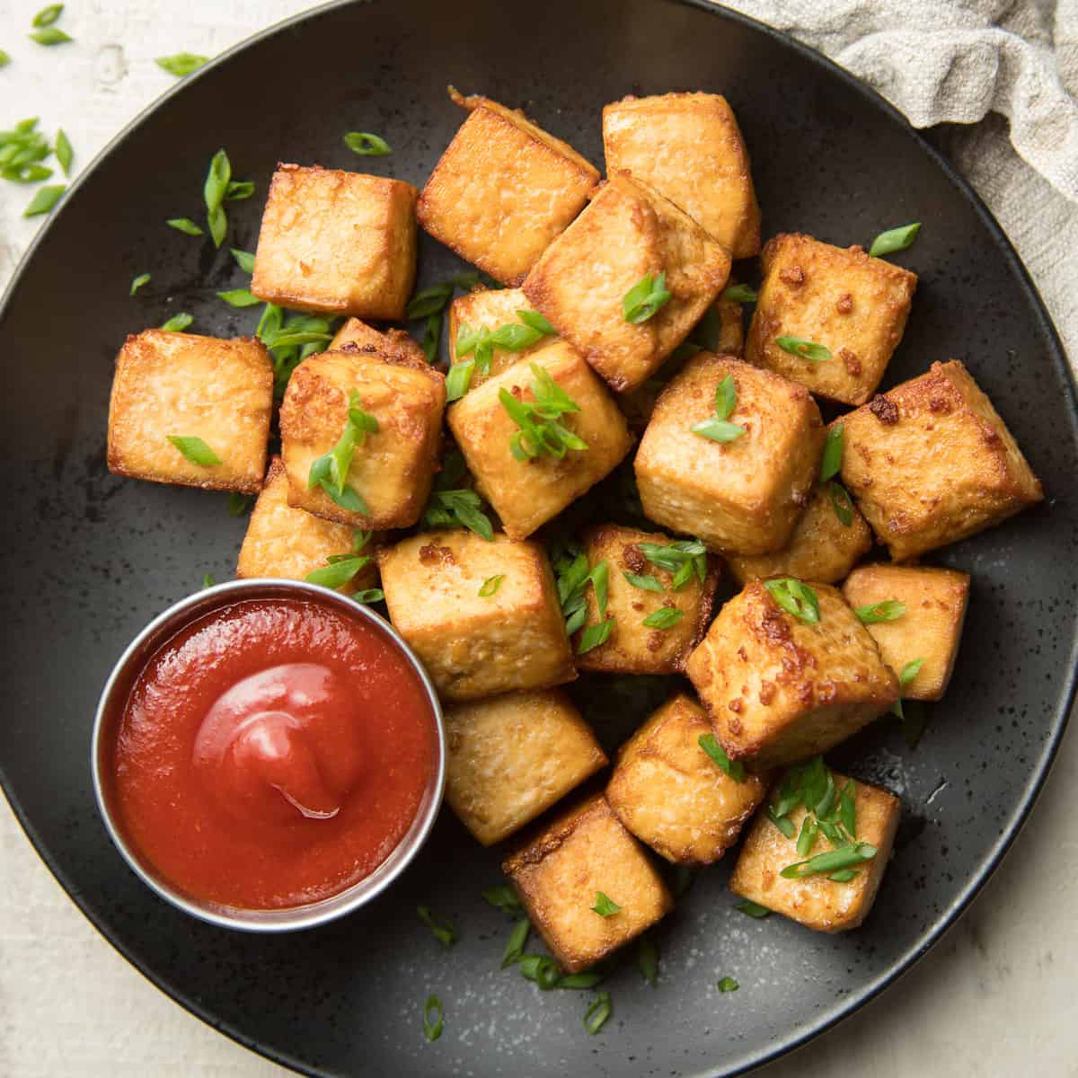 Plate of Air Fryer Tofu with Chives on Top and Sauce on the Side