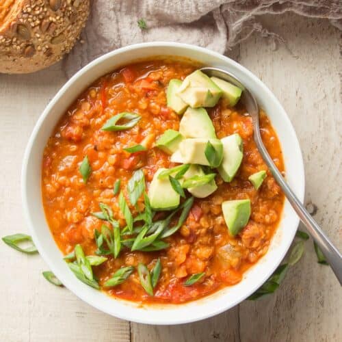 Bowl of Red Lentil Chili Topped with Scallions and Avocado