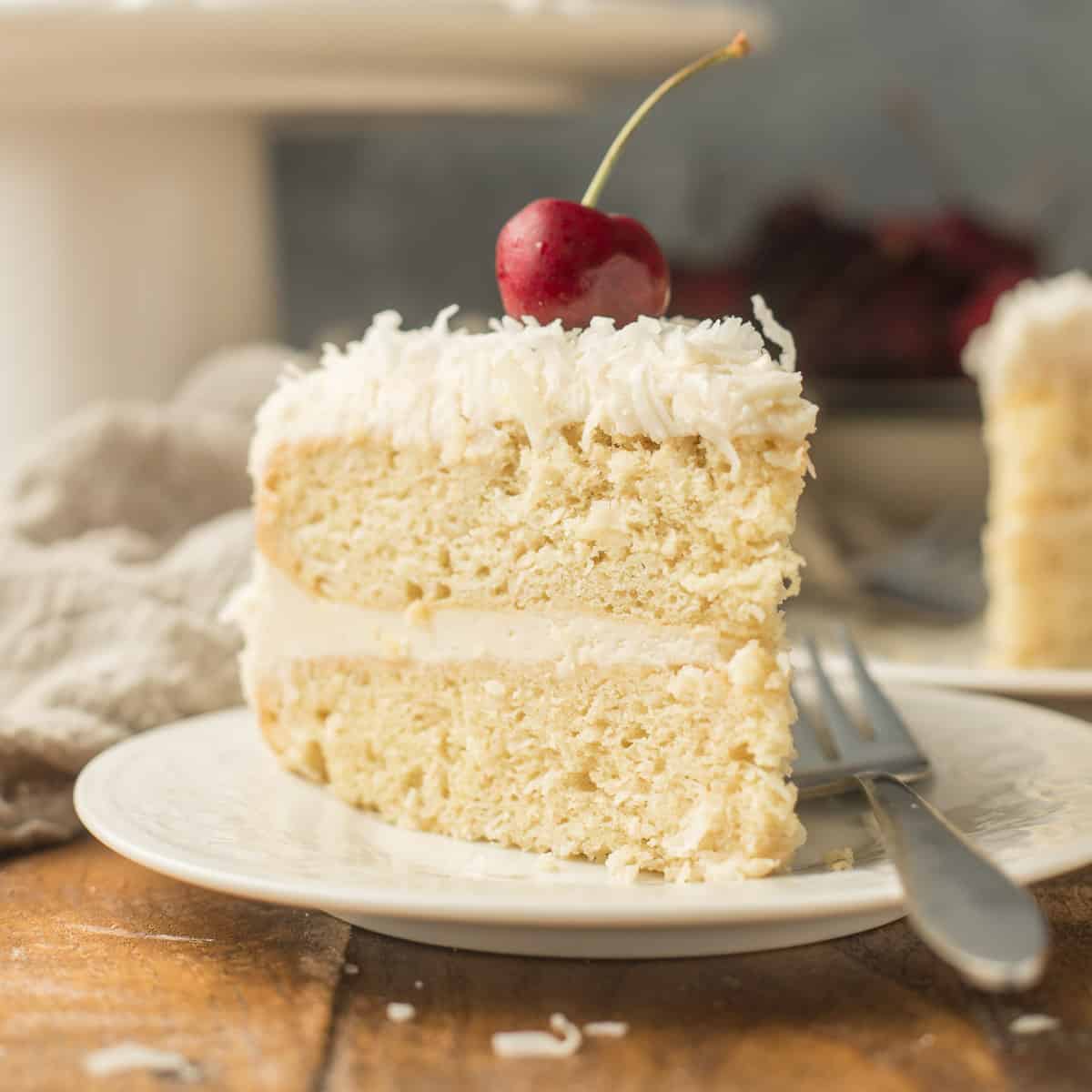 Slice of Vegan Coconut Cake on a Plate with a Cherry on Top