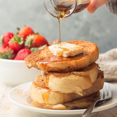 Hand Pouring Maple Syrup Over a Stack of Vegan French Toast