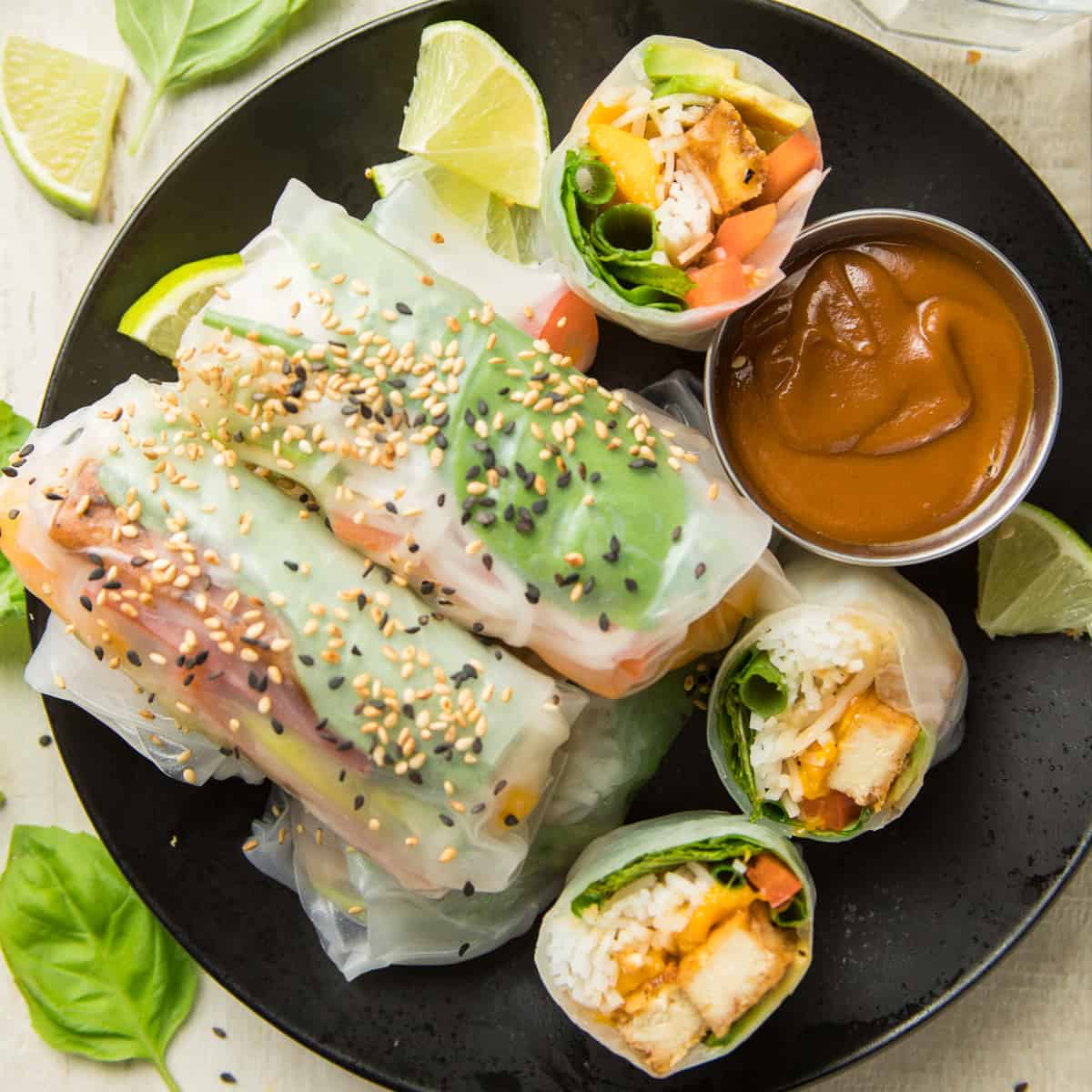 Vegan Summer Rolls Topped with Sesame Seeds and Dish of Peanut Sauce on a Plate
