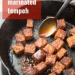 Spoon drizzling marinade over tempeh with text overlay reading "Smoky Marinated Tempeh".