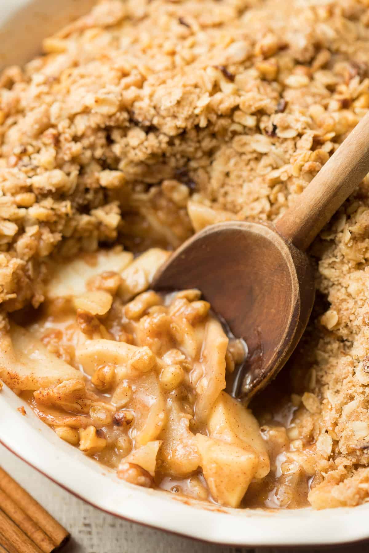 Close Up of Wooden Spoon Scooping Vegan Apple Crisp From a Baking Dish