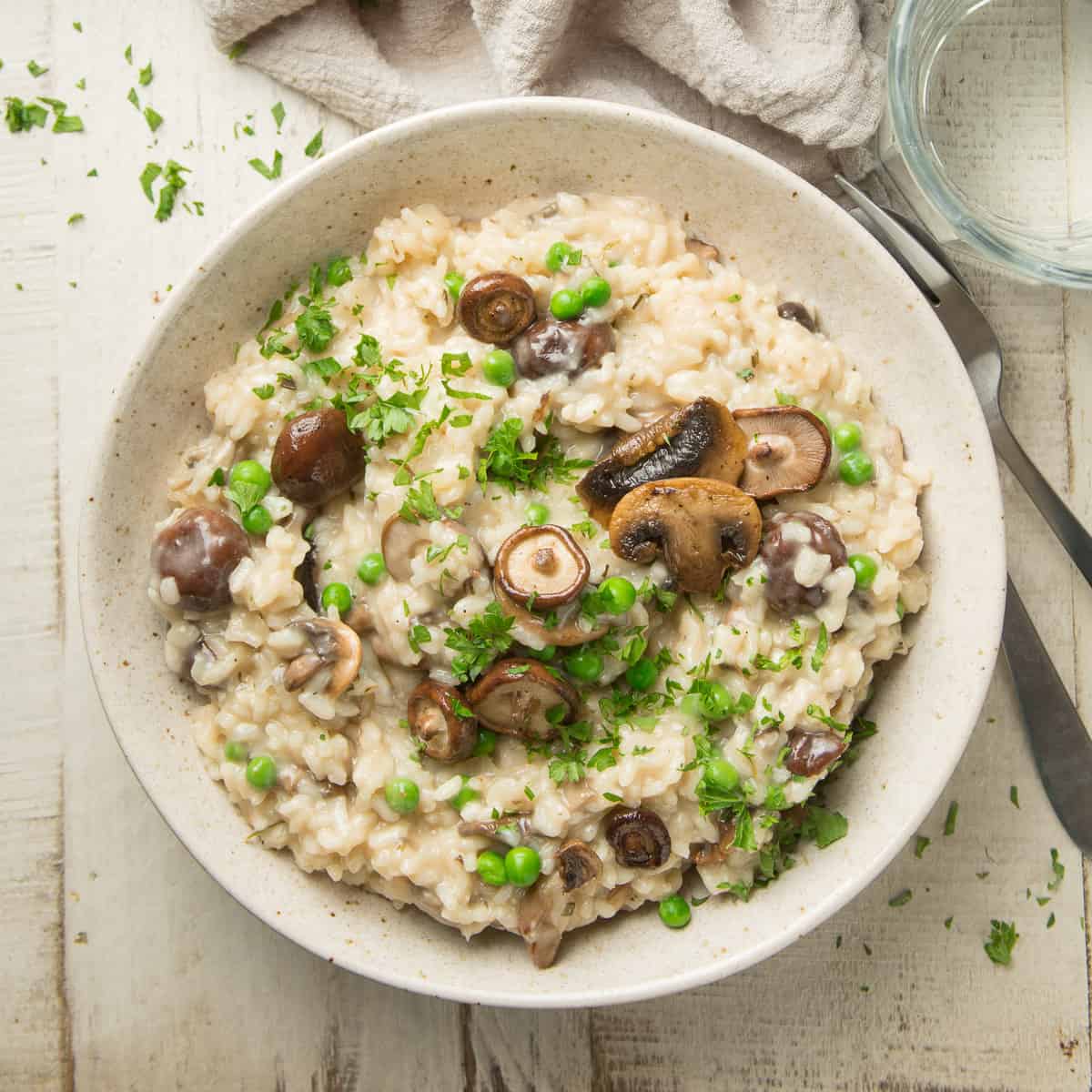 Bowl of Vegan Mushroom Risotto on a white wooden surface.