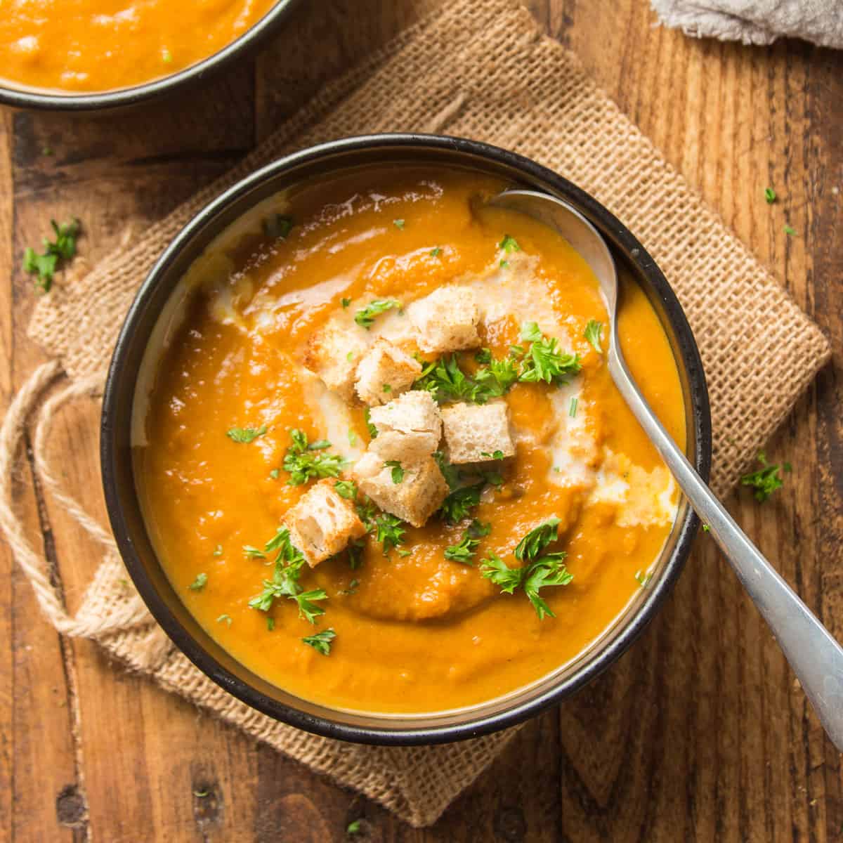 Bowl of Vegan Pumpkin Soup Topped with Parsley and Croutons