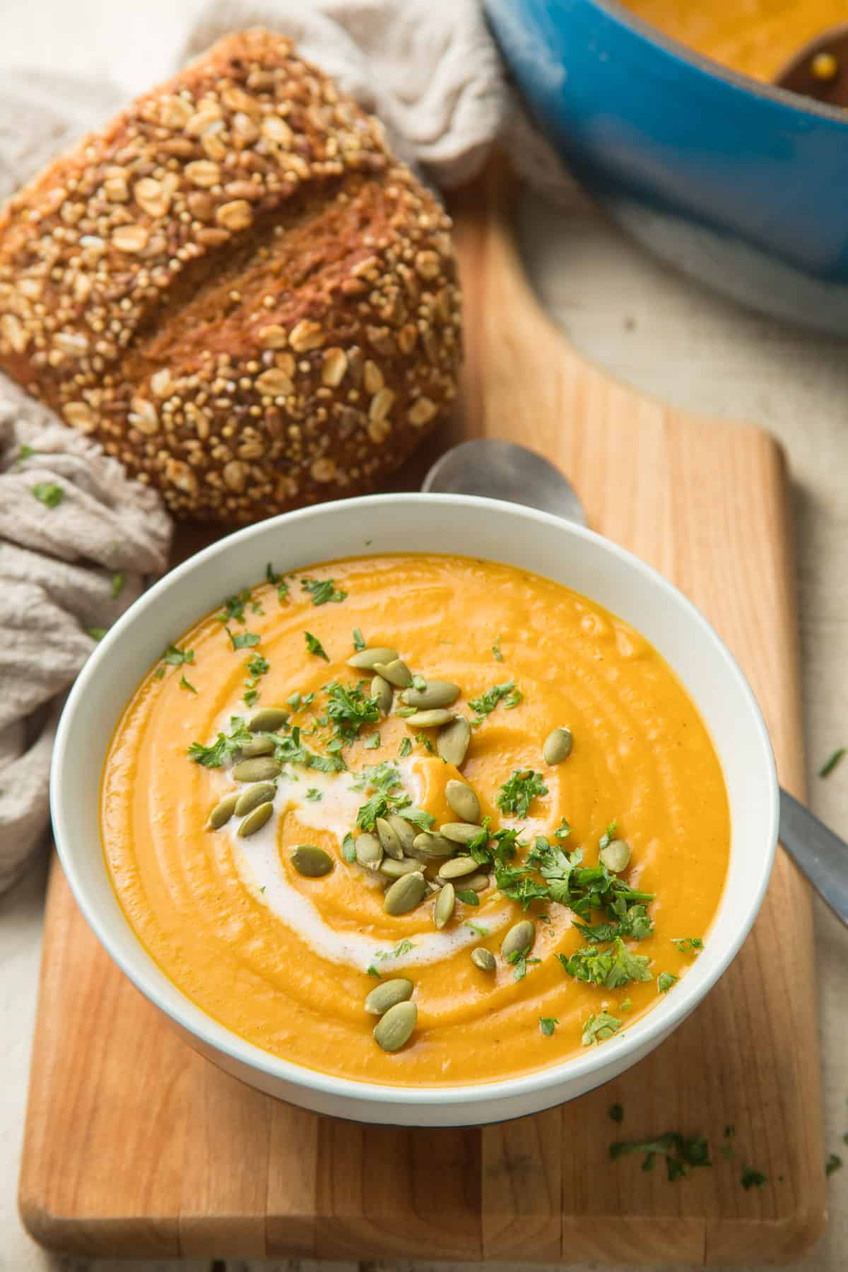 Bowl of Vegan Butternut Squash Soup Topped with Parsley and Pumpkin Seeds.