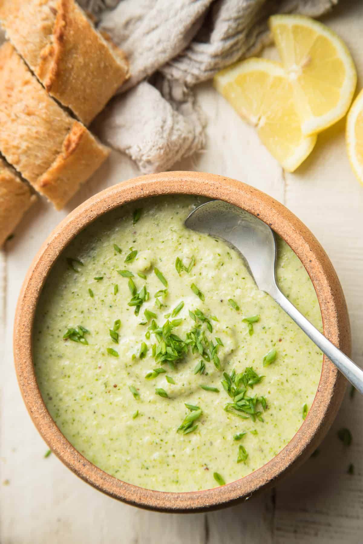 Bowl of Vegan Cream of Broccoli Soup with a Spoon in it and Chives on Top