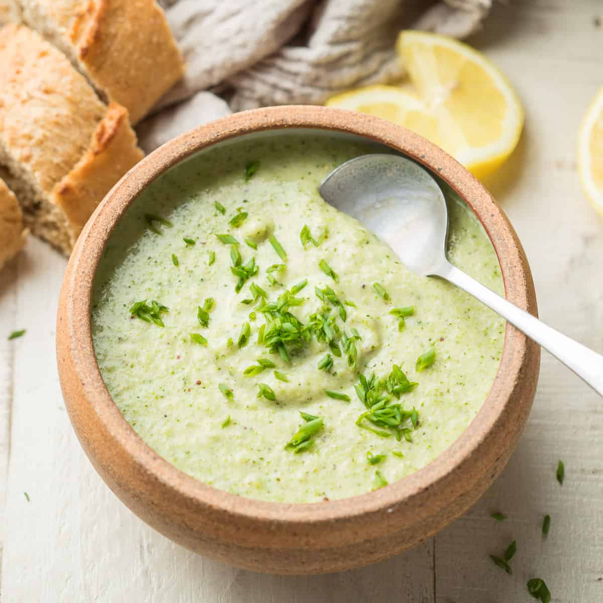 Bowl of Vegan Cream of Broccoli Soup with Lemon and Bread Slices in the Background