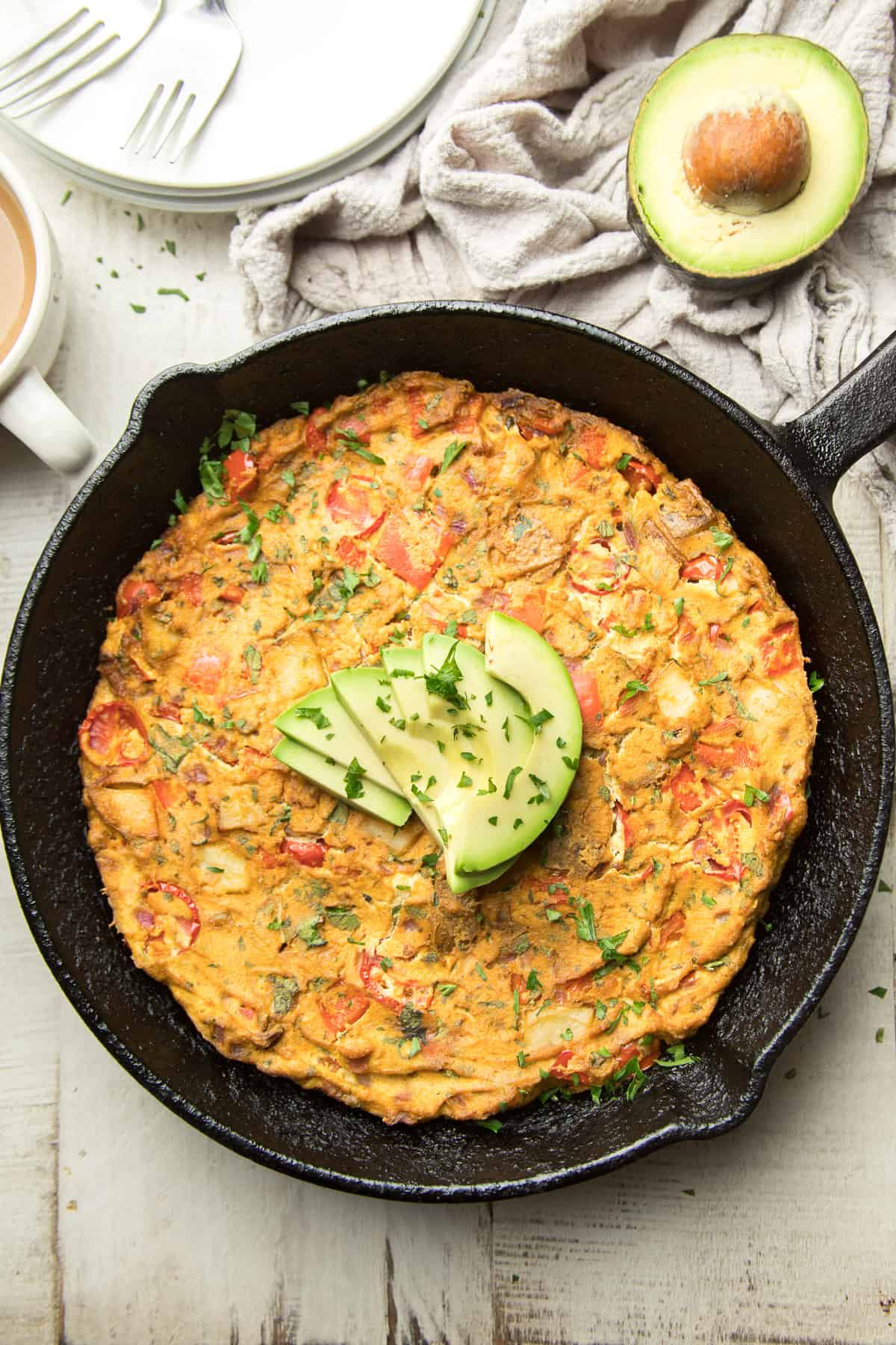 Whole Vegan Frittata in a skillet with avocado slices on top.