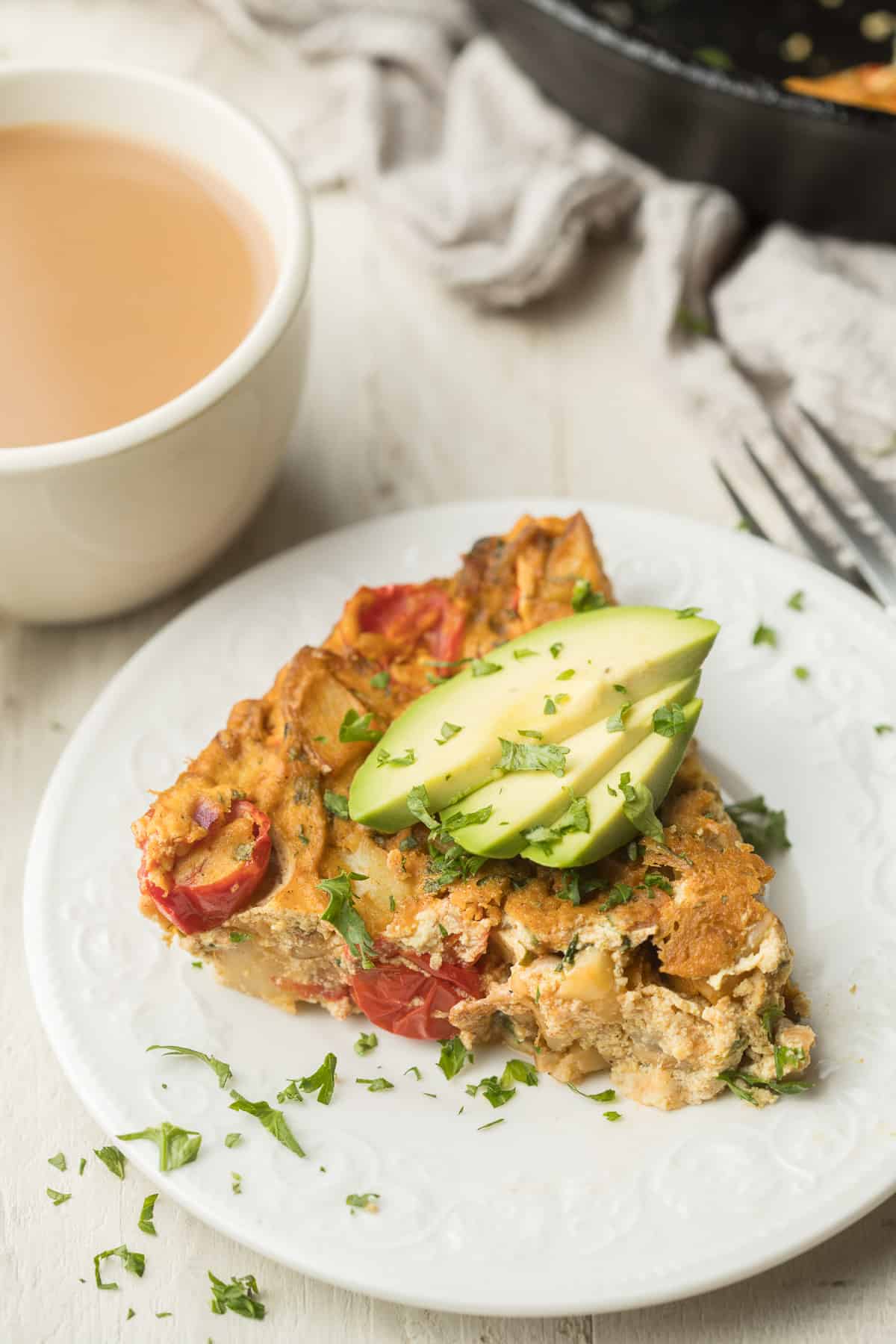 Slice of Vegan Frittata on a plate with avoacdo slices on top.