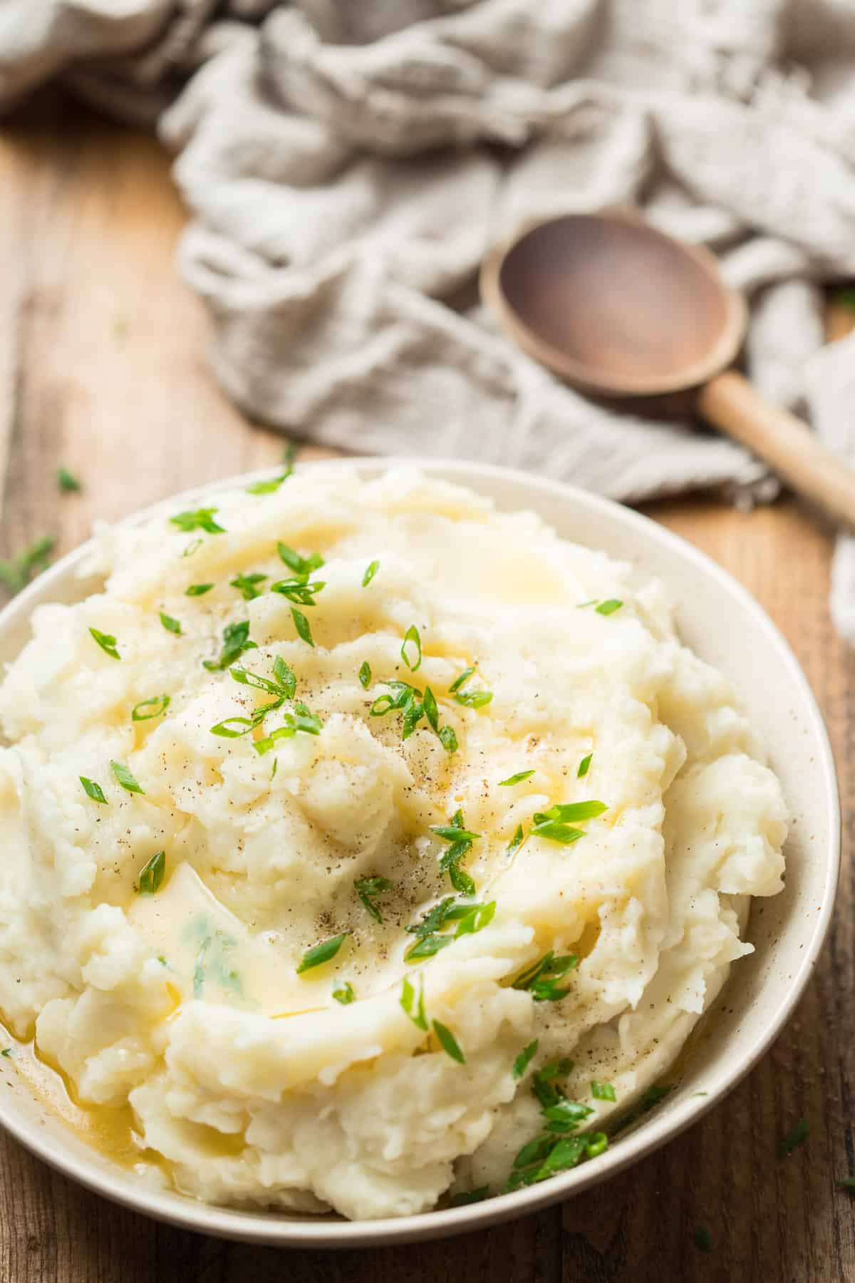 Bowl of Vegan Mashed Potatoes with Wooden Spoon in the Background.