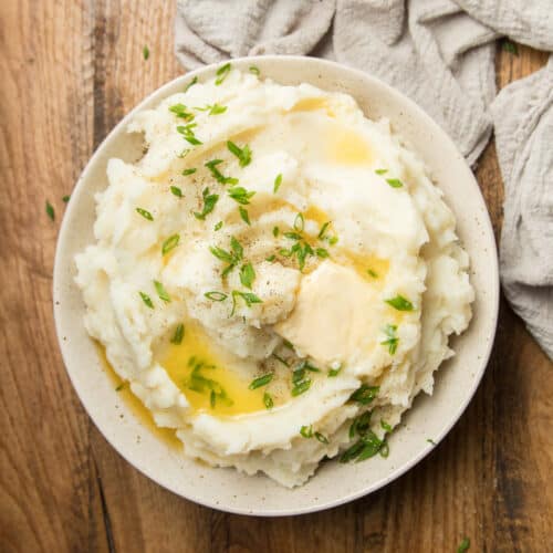 Bowl of Vegan Mashed Potatoes Topped with Butter and Chives.