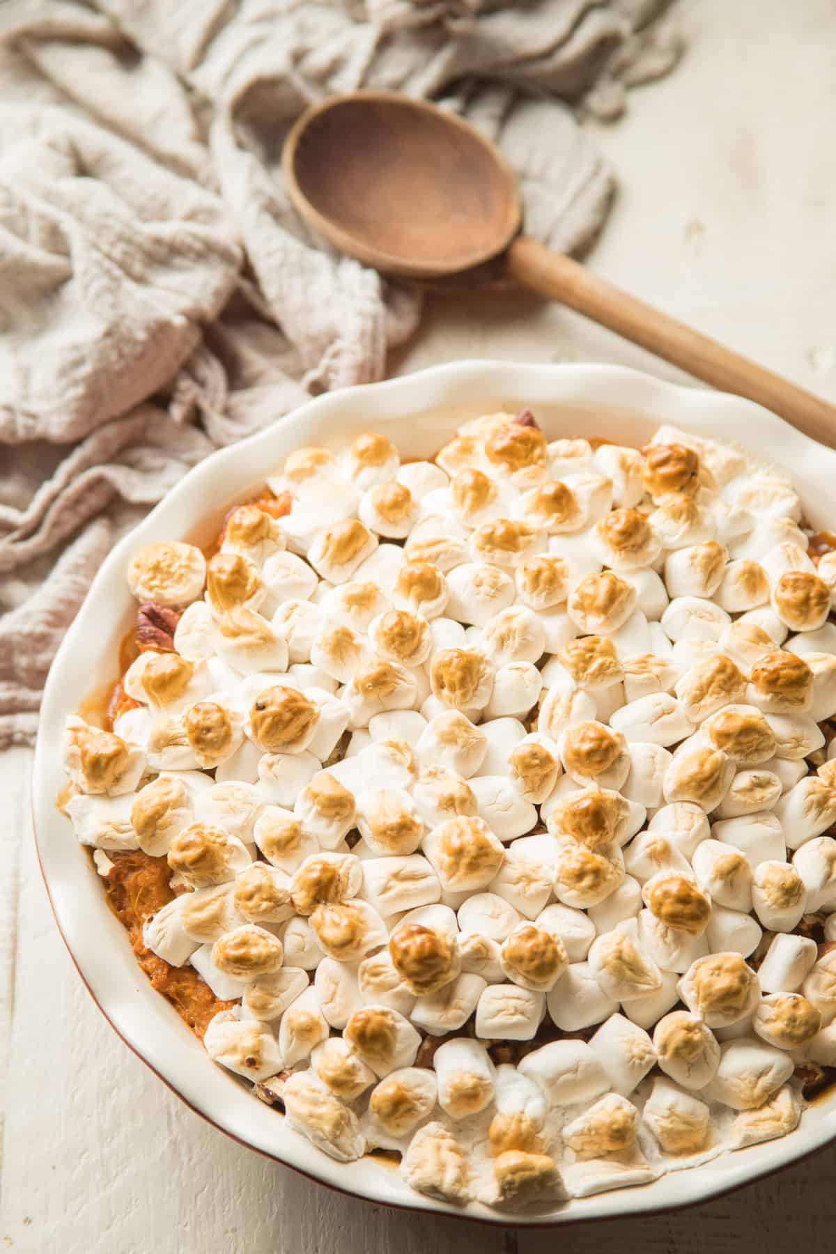 Dish of Marshmallow Vegan Sweet Potato Casserole with Spoon in the background.