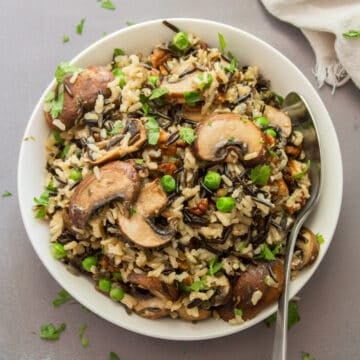 A Bowl of Wild Rice Pilaf with Mushrooms and Pecans with Serving Spoon