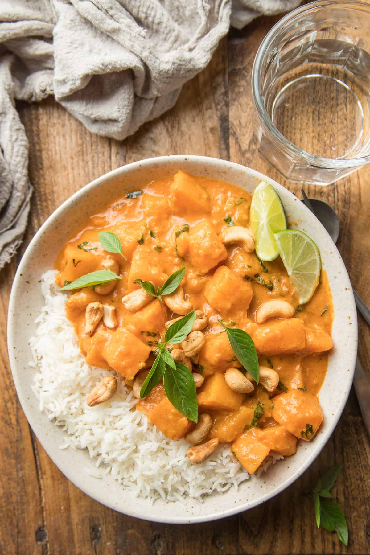 Bowl of Pumpkin Curry and rice topped with cashews and fresh basil.