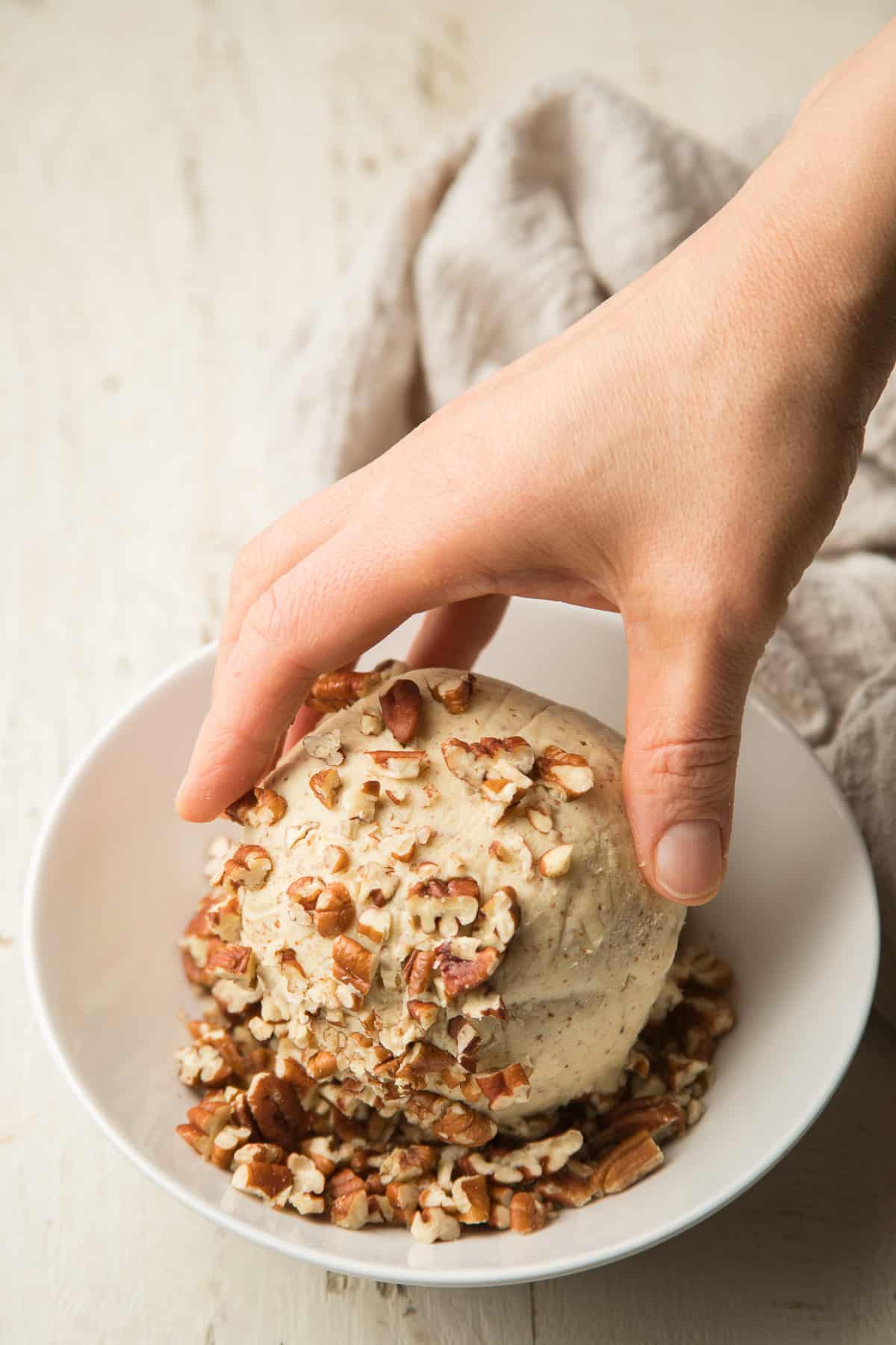 Hand Rolling a Vegan Cheese Ball in Pecans.