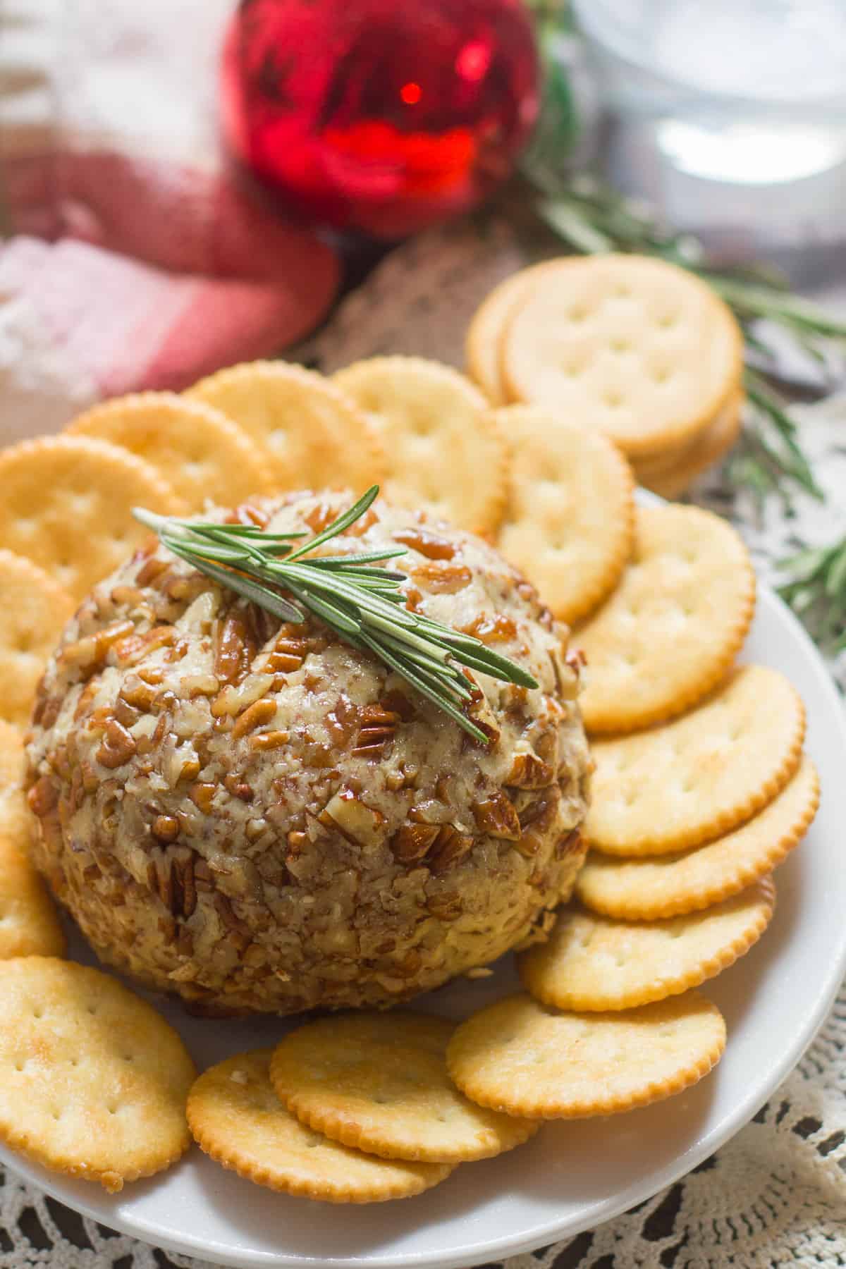 Vegan Cheese Ball Surrounded By Crackers with a Sprig of Rosemary on Top