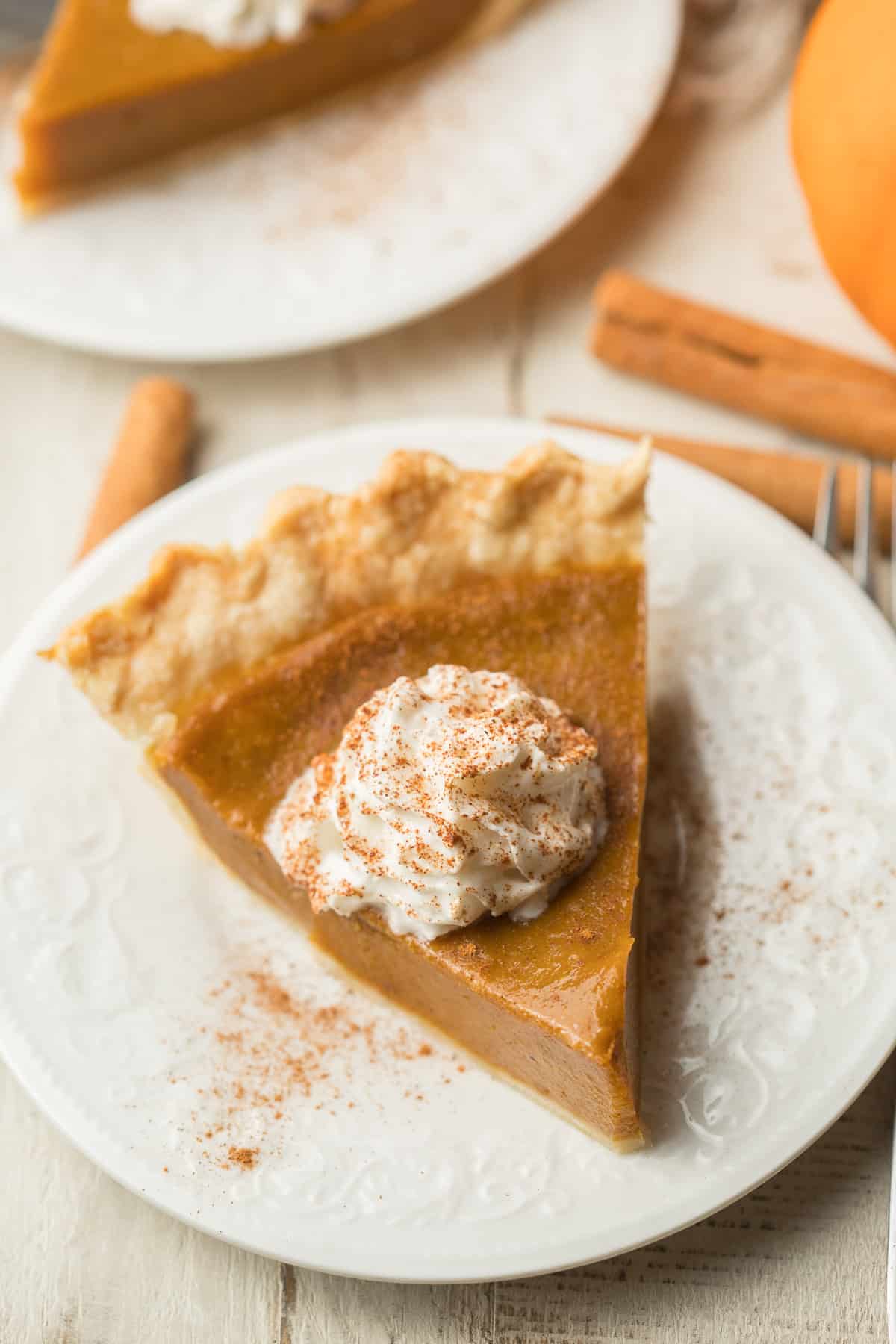 Slice of Vegan Pumpkin Pie Topped with Whipped Topping and Cinnamon.