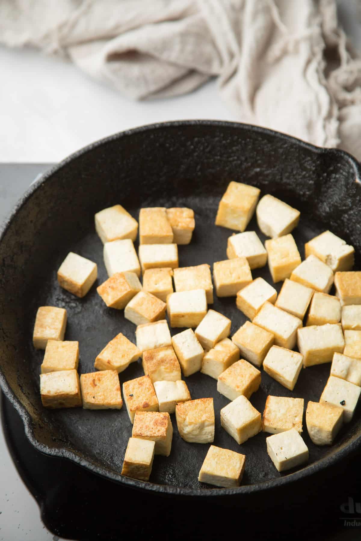 Tofu Cubes frying in a skillet.