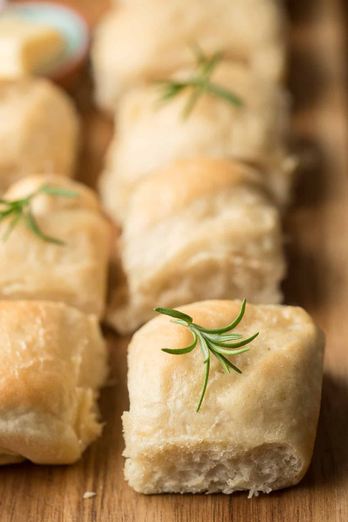 Vegan Dinner Rolls on a cutting board with rosemary sprigs on top.