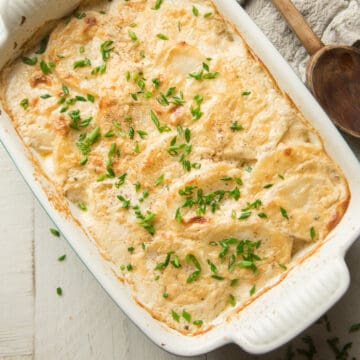 Dish of Vegan Scalloped Potatoes with wooden spoon on the side.