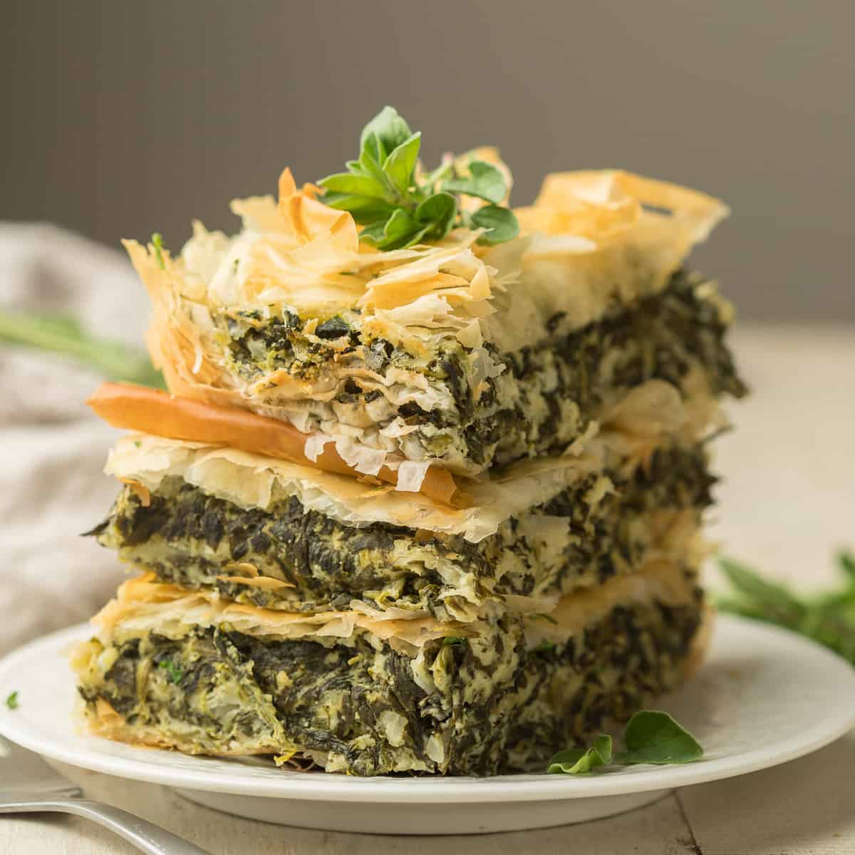Three stacked slices of Vegan Spanakopita on a plate.